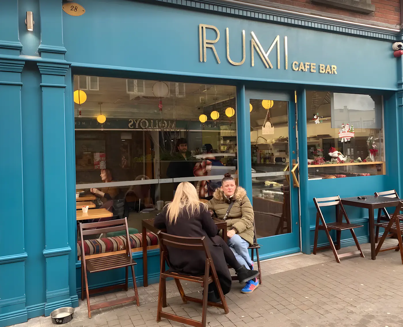 The teal-blue Rumi Cafe Bar storefront at 28 Francis Street, with guests at the outdoor tables